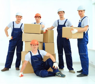 Professional commercial movers preparing office furniture for transport in Poplar